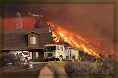 A United States Forest Service air tanker drops fire retardant next to a line of fire as the Station fire burns in the hills above a home in Acton last night (AP Photo/Dan Steinberg)